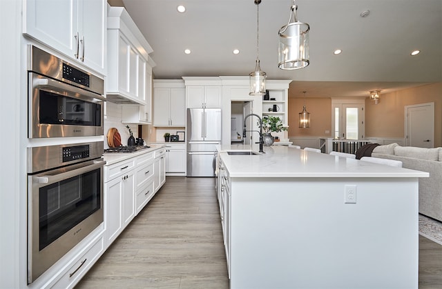 kitchen featuring appliances with stainless steel finishes, sink, hanging light fixtures, a large island, and white cabinets