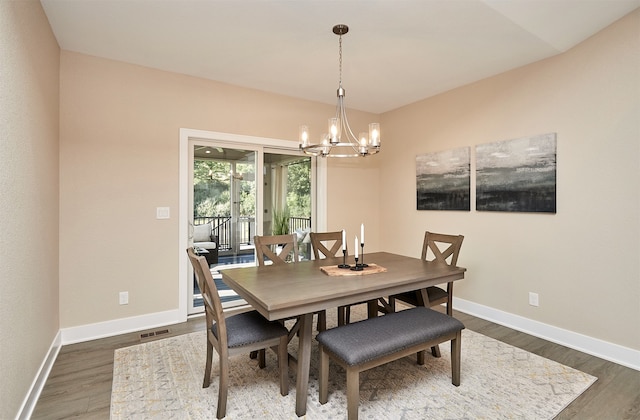 dining area with dark wood-type flooring and a notable chandelier