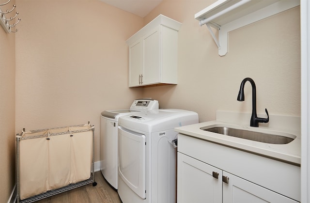 washroom featuring cabinets, light hardwood / wood-style flooring, sink, and washer and clothes dryer