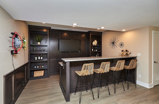 bar with a textured ceiling and light wood-type flooring