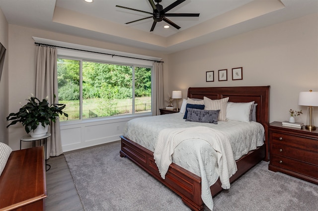 bedroom with ceiling fan, a raised ceiling, and light hardwood / wood-style flooring