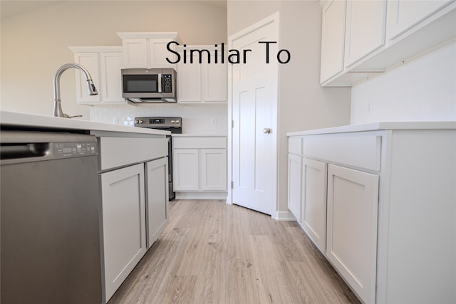 kitchen with decorative backsplash, white cabinets, stainless steel appliances, and light wood-type flooring