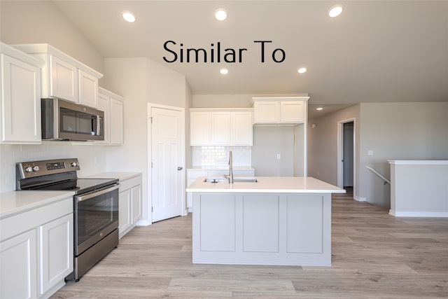 kitchen featuring tasteful backsplash, appliances with stainless steel finishes, sink, white cabinetry, and a center island with sink