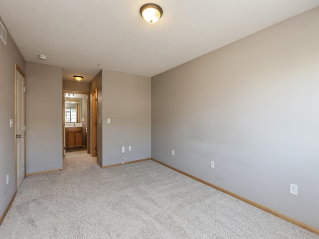 spare room with light colored carpet and a textured ceiling