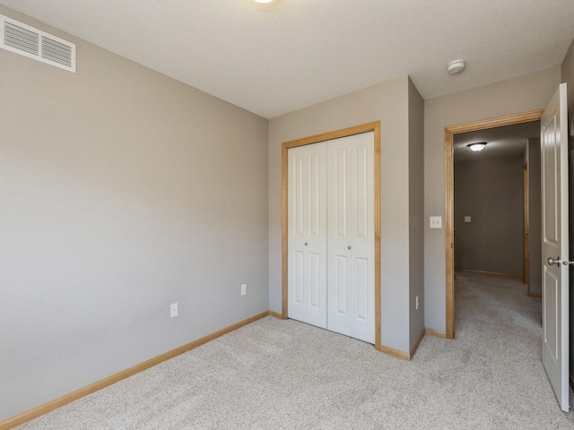 unfurnished bedroom featuring a closet, light colored carpet, and a textured ceiling