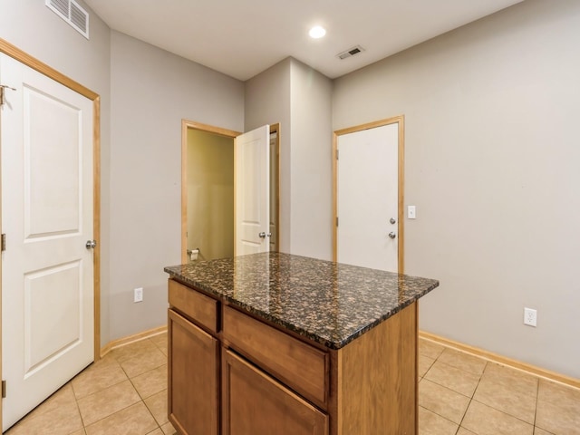 kitchen featuring a center island, light tile patterned floors, and dark stone counters