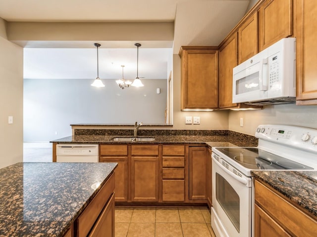 kitchen with sink, dark stone counters, pendant lighting, white appliances, and light tile patterned floors