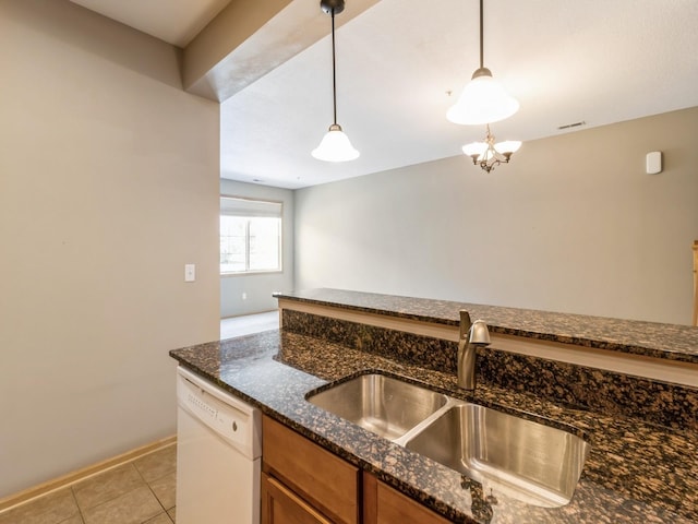 kitchen featuring dishwasher, sink, hanging light fixtures, dark stone countertops, and a chandelier