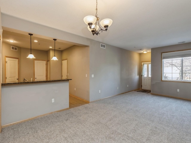 carpeted spare room featuring a notable chandelier