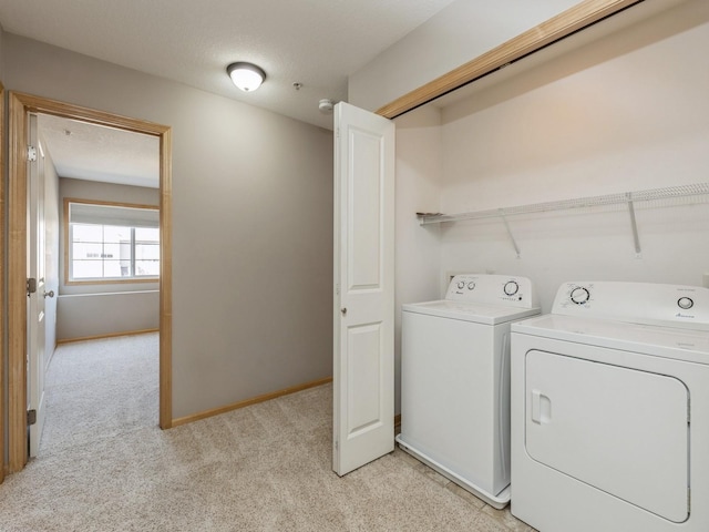 laundry room featuring a textured ceiling, washing machine and dryer, and light carpet