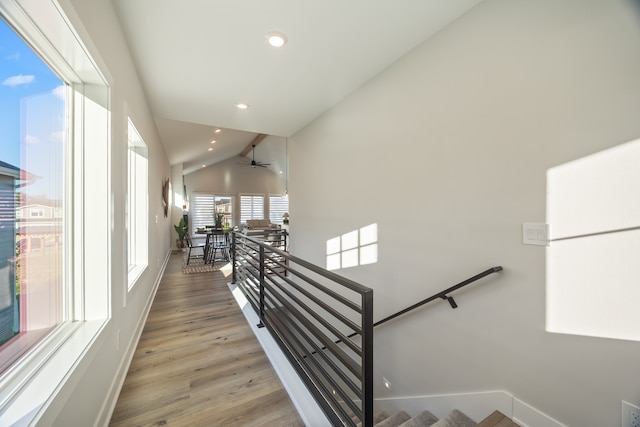 stairs with hardwood / wood-style floors, ceiling fan, and lofted ceiling