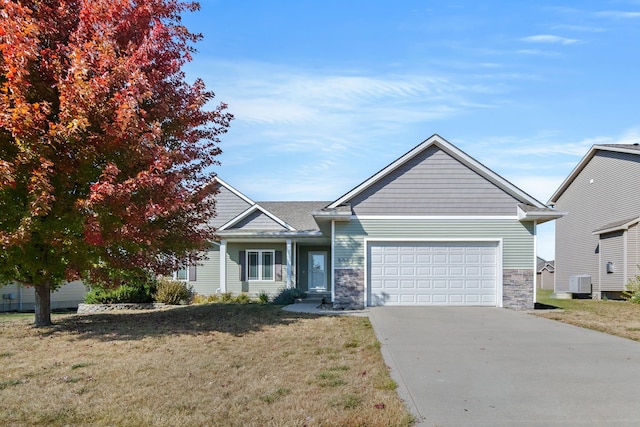 view of front of home with cooling unit, a garage, and a front yard