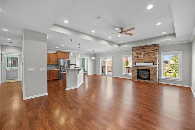 unfurnished living room featuring dark wood-style floors, a raised ceiling, a wealth of natural light, and baseboards