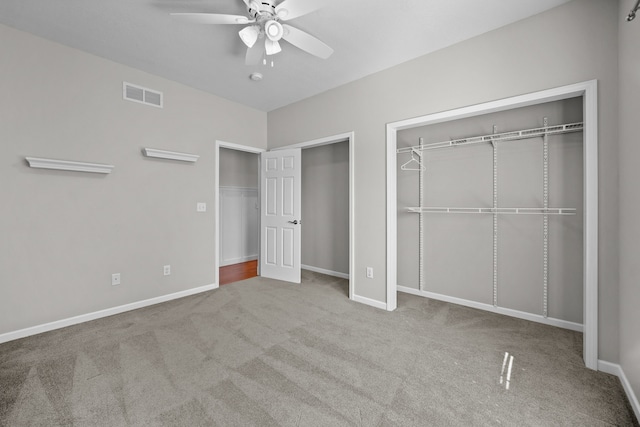 unfurnished bedroom featuring light carpet, multiple closets, baseboards, a ceiling fan, and visible vents