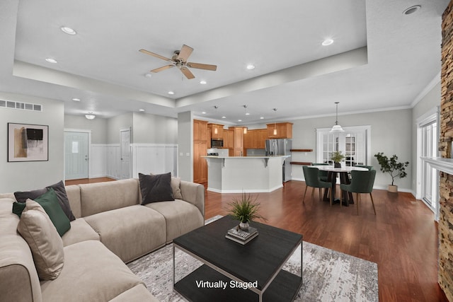 living area with a raised ceiling, recessed lighting, and wood finished floors