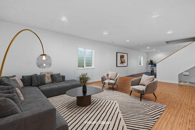 living area featuring recessed lighting, baseboards, light wood-type flooring, and stairs