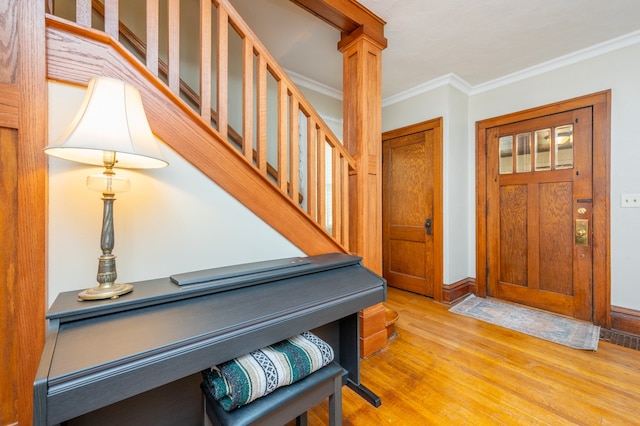 foyer entrance with light hardwood / wood-style flooring, ornamental molding, and decorative columns