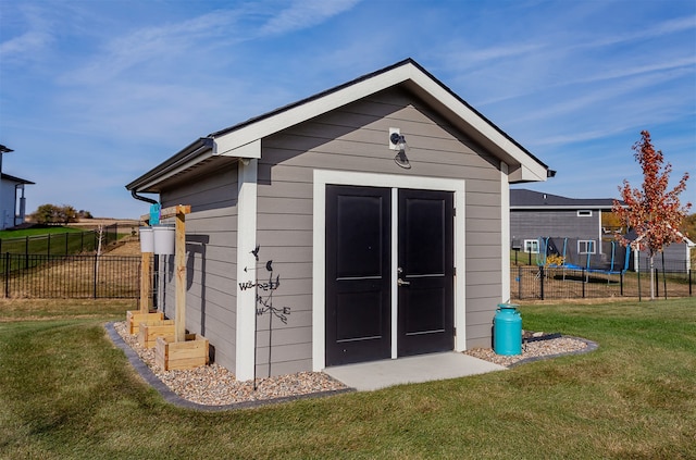 view of outbuilding featuring a trampoline and a lawn