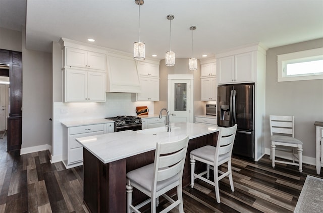 kitchen featuring custom exhaust hood, appliances with stainless steel finishes, decorative light fixtures, and white cabinetry