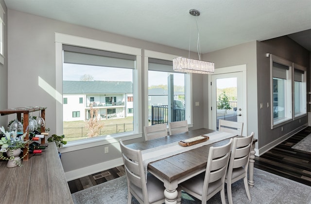 dining area with dark wood-type flooring and an inviting chandelier