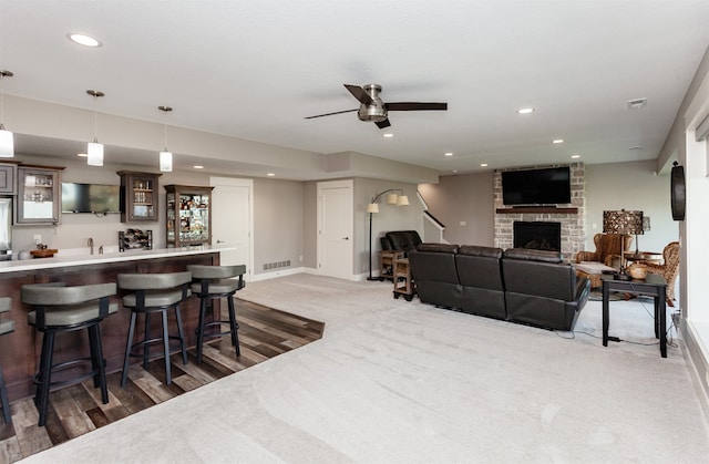 interior space with ceiling fan, a brick fireplace, indoor bar, and hardwood / wood-style floors