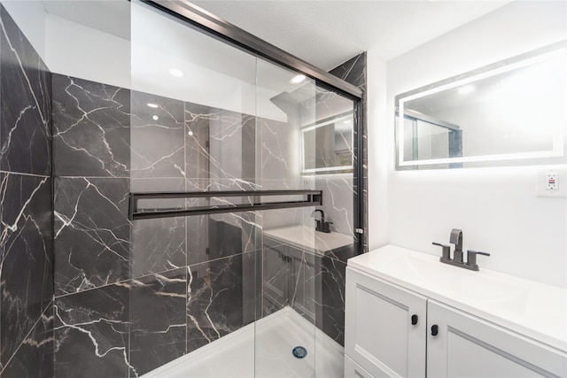 full bathroom with a marble finish shower and vanity