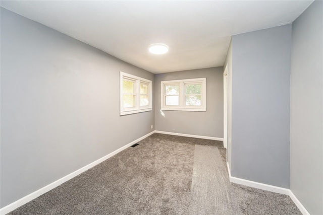 unfurnished room with visible vents, baseboards, and carpet flooring