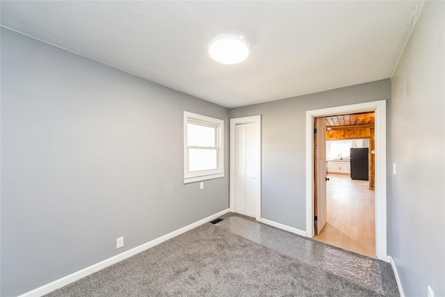 unfurnished bedroom featuring visible vents, baseboards, a closet, and freestanding refrigerator