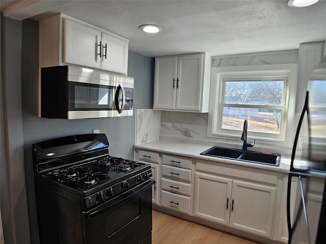 kitchen featuring light wood-style flooring, a sink, stainless steel appliances, light countertops, and backsplash