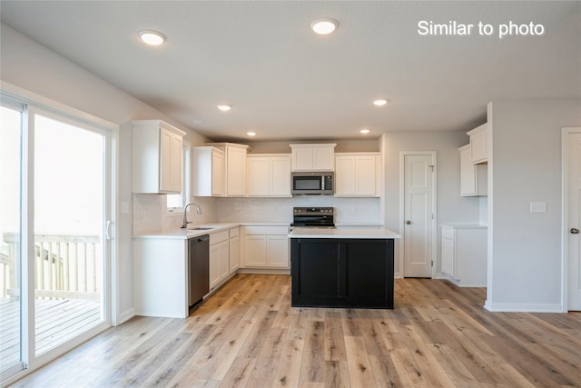 kitchen with white cabinetry, light hardwood / wood-style flooring, a kitchen island, and stainless steel appliances