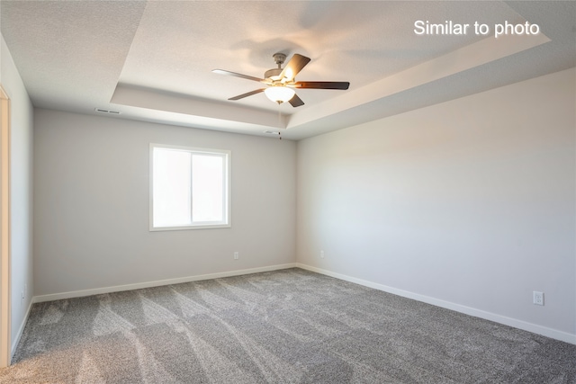 carpeted spare room featuring ceiling fan, a raised ceiling, and a textured ceiling