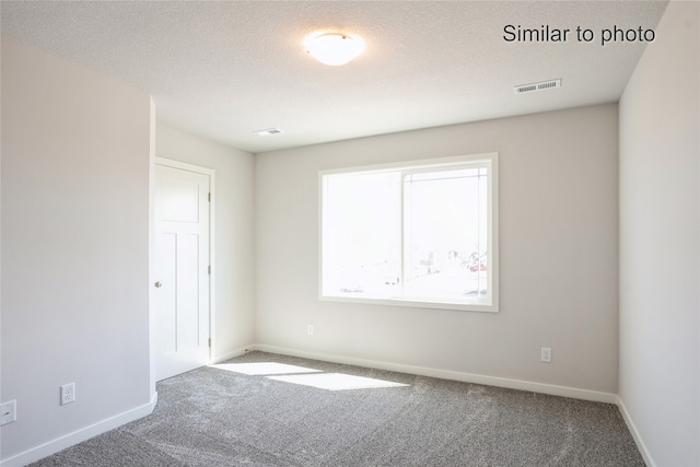 carpeted empty room with a textured ceiling