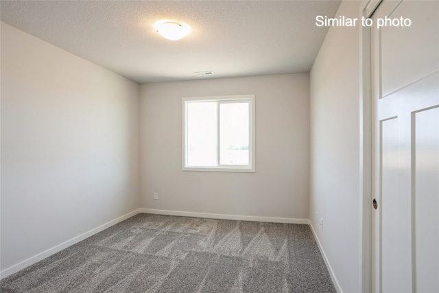 carpeted spare room with a textured ceiling