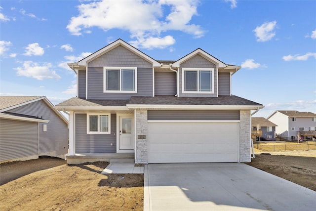 view of front of home with stone siding, roof with shingles, concrete driveway, and an attached garage