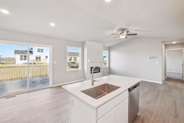 kitchen featuring dishwasher, lofted ceiling, white cabinetry, sink, and a kitchen island with sink