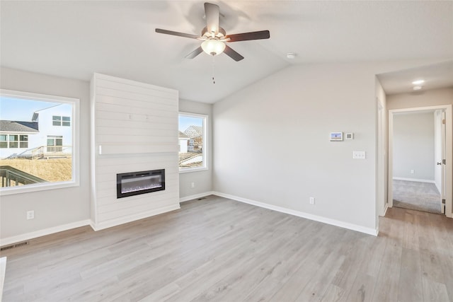 unfurnished living room featuring vaulted ceiling, ceiling fan, a large fireplace, and light hardwood / wood-style flooring