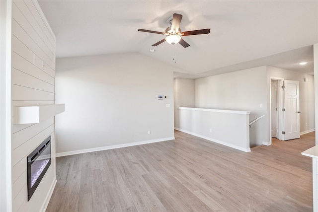 unfurnished living room with ceiling fan, a large fireplace, lofted ceiling, and light hardwood / wood-style flooring