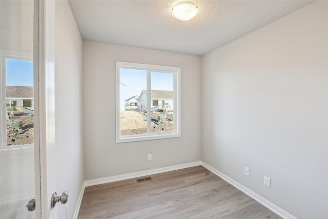 empty room with a textured ceiling and light wood-type flooring