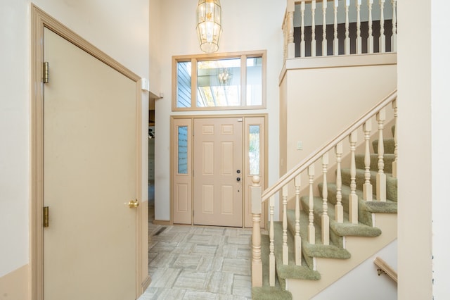 foyer entrance with stairs, an inviting chandelier, and a towering ceiling