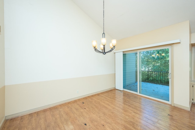 spare room with an inviting chandelier, wood finished floors, baseboards, and high vaulted ceiling