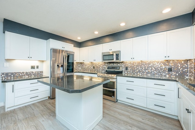 kitchen with tasteful backsplash, white cabinets, appliances with stainless steel finishes, and dark countertops