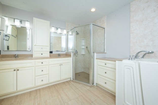 bathroom featuring double vanity, a stall shower, and a sink