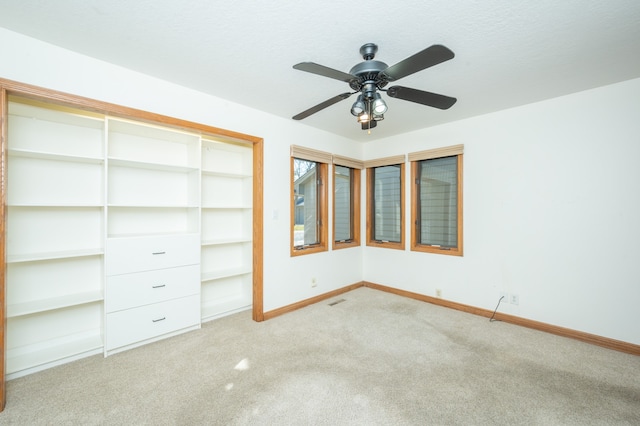 unfurnished bedroom with carpet flooring, a ceiling fan, baseboards, and a textured ceiling