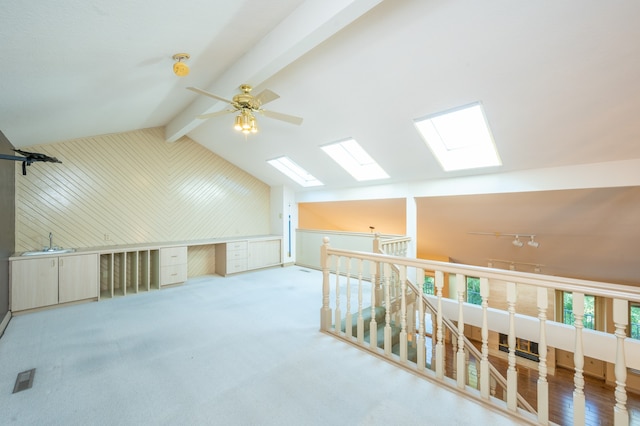 additional living space featuring a ceiling fan, visible vents, vaulted ceiling with beams, a sink, and carpet flooring