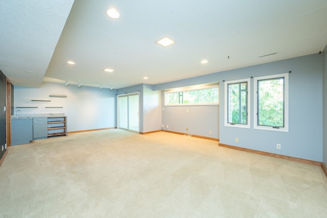 interior space with a sink, baseboards, light carpet, and track lighting