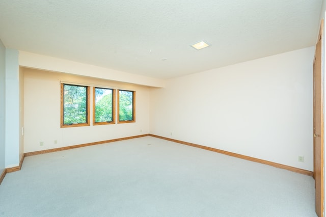 carpeted empty room featuring a textured ceiling and baseboards