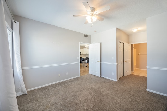 unfurnished bedroom featuring ceiling fan, a closet, and light colored carpet