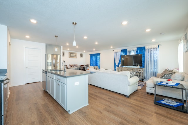 kitchen featuring hanging light fixtures, an island with sink, light hardwood / wood-style flooring, sink, and stainless steel appliances
