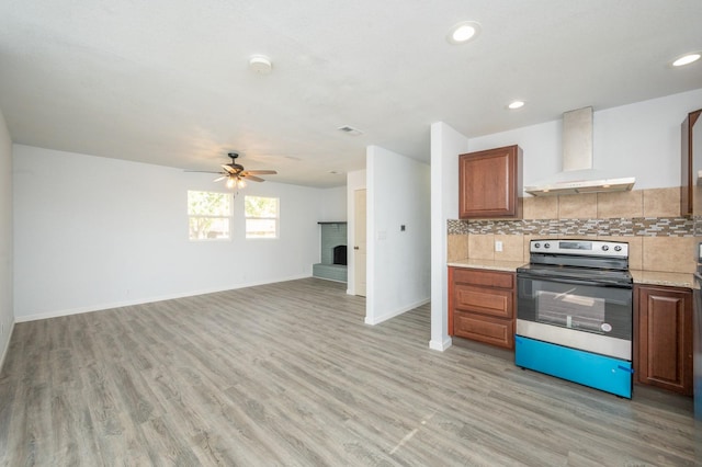 kitchen featuring tasteful backsplash, electric range, ceiling fan, wall chimney range hood, and light hardwood / wood-style flooring