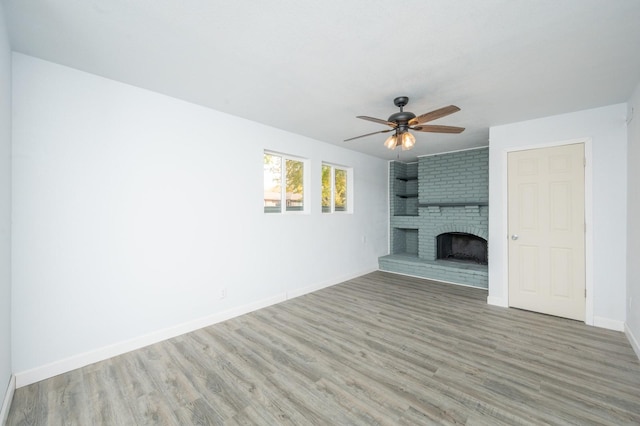 unfurnished living room featuring ceiling fan, wood-type flooring, and a fireplace